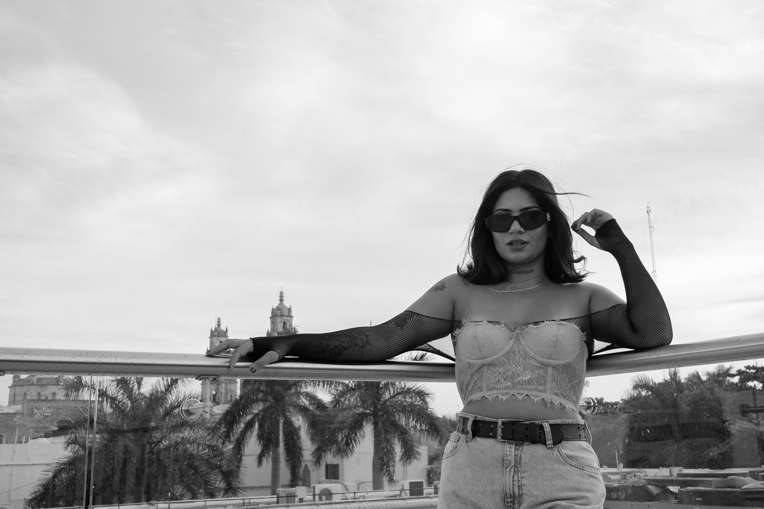 Black and White Photo of a Young Woman in a Trendy Outfit Standing on a Terrace